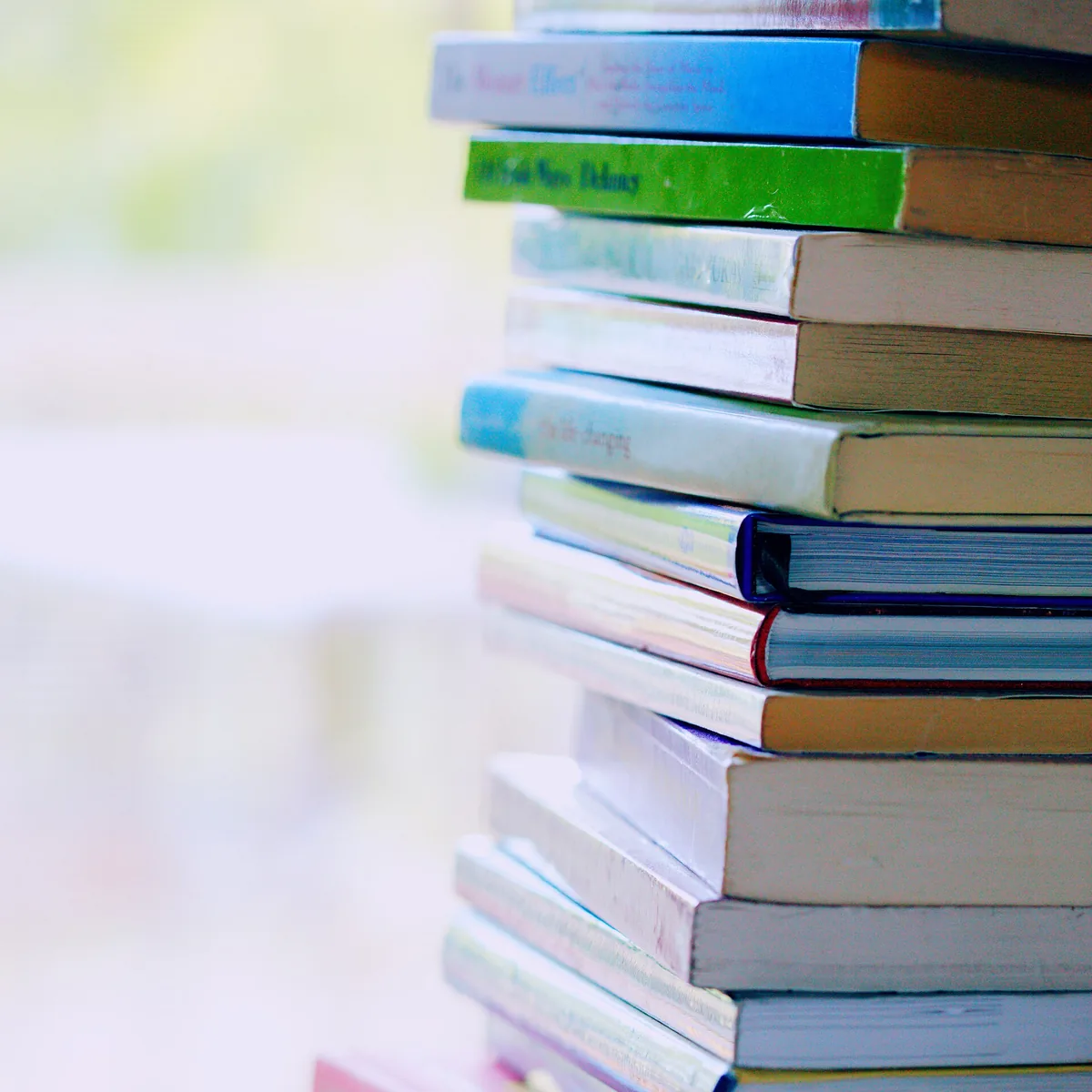 Tall stack of closed books on a table, spines turned outward